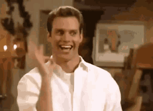 a man in a white shirt is making a funny face and laughing .