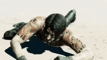 a man with a lot of tattoos on his body is crawling on the ground