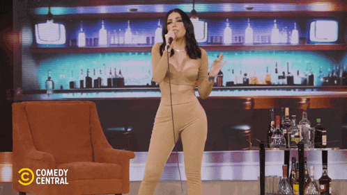 a woman singing into a microphone with comedy central written on the bottom