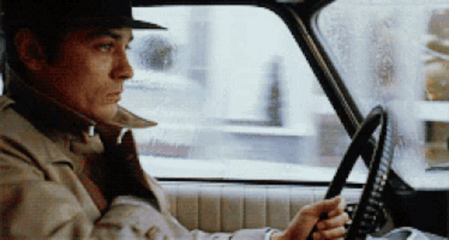 a man wearing a hat is driving a car