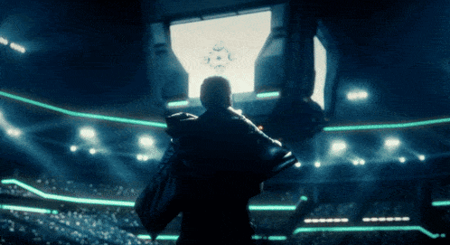 a man in a black jacket stands in front of a large screen that says ' y ' on it