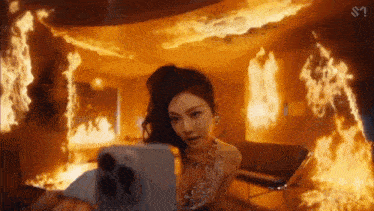 a woman is taking a selfie in front of a room full of flames .