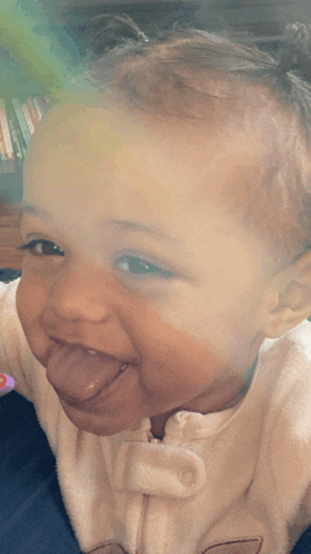 a baby is sticking its tongue out and smiling for the camera