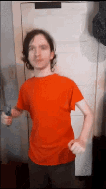 a young man in a red shirt is standing in front of a white door