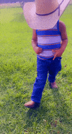a young boy wearing a cowboy hat and a striped shirt is walking in the grass