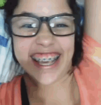 a woman wearing braces and glasses is smiling