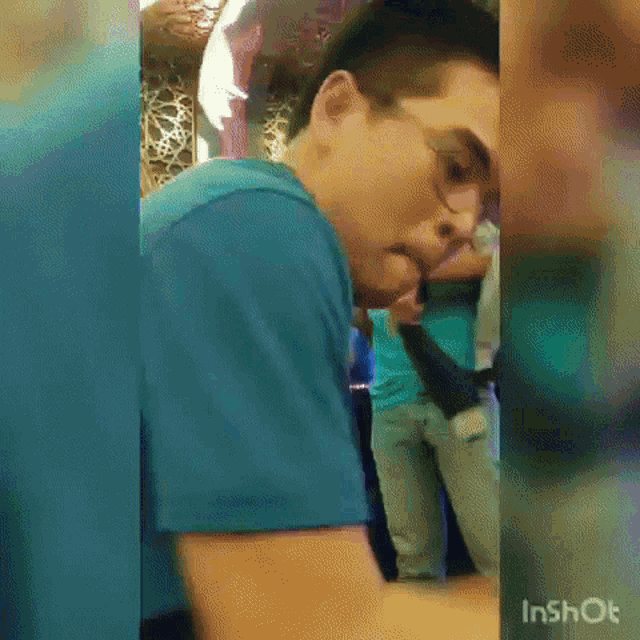 a man wearing glasses and a blue shirt is standing in front of a crowd .