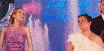 a group of women are standing in front of a waterfall .