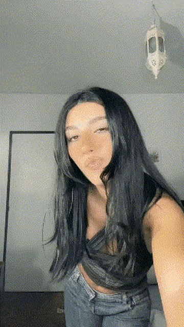 a woman with long dark hair is taking a selfie in front of a mirror .