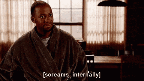 a man in a bathrobe screams internally in front of a window