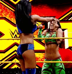 two women are wrestling in a ring with the letter w on the wall behind them