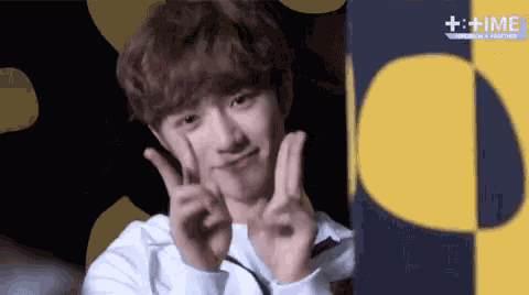 a young man is making a peace sign with his hands