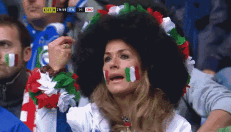 a woman wearing an afro wig and a wreath around her neck is watching a game between italy and cro