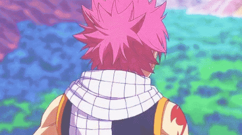 a man with pink hair and a scarf around his neck is standing in front of a field .