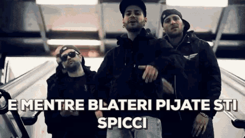 a group of men are standing next to each other on an escalator with the words " e mentre blateri pijate sti spicci "