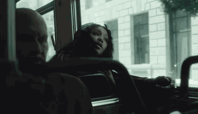 a man and a woman are sitting on a bus and looking out the window