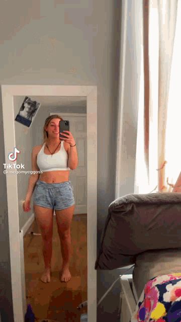a woman is taking a selfie in front of a mirror in a room .
