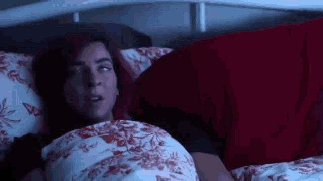 a woman with red hair is laying in bed with a red blanket and a red pillow .