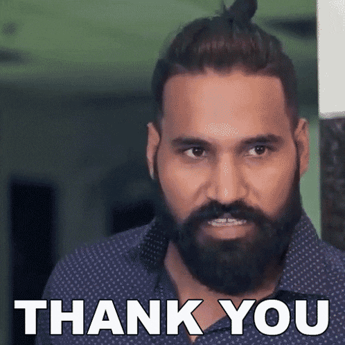 a man with a beard is giving a thank you sign .