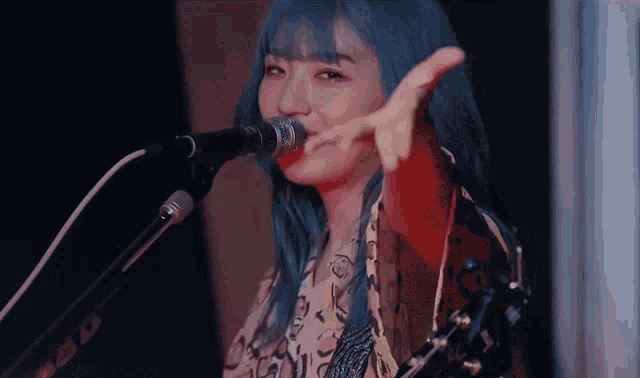 a woman with blue hair singing into a microphone with the letter o on it