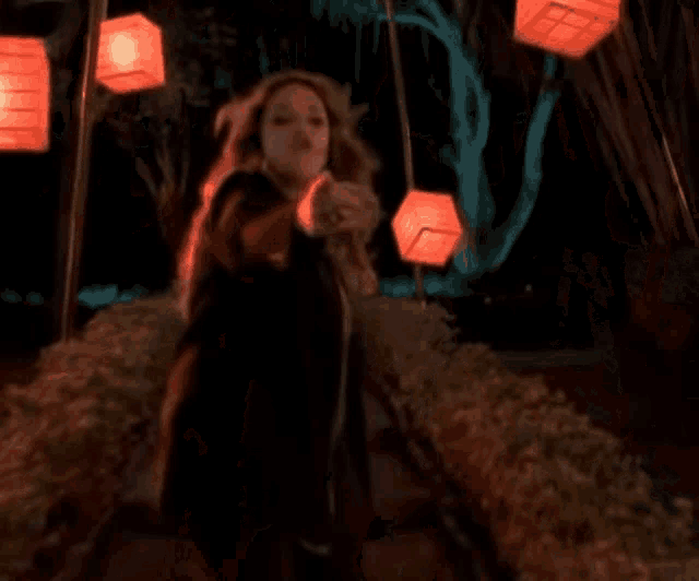 a woman in a black dress is walking through a tunnel of red lights