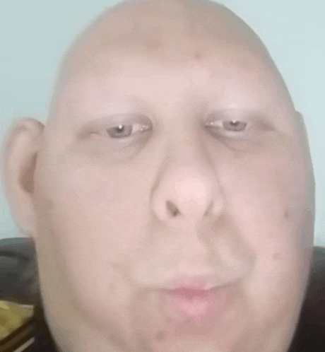 a close up of a bald man 's face with a very funny face .