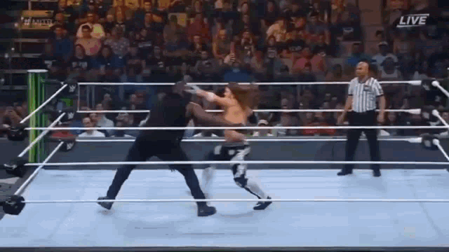 two men are wrestling in a wrestling ring with a referee .