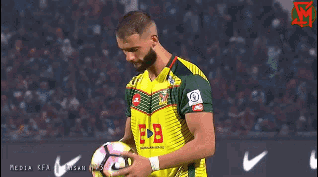 a man holding a soccer ball with the letters eb on his shirt