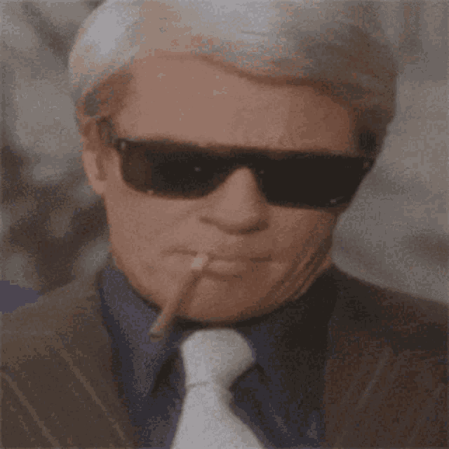 a man wearing sunglasses smoking a pipe in his mouth