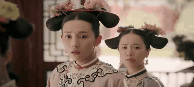 two women are standing next to each other in a room wearing traditional clothes and hats .