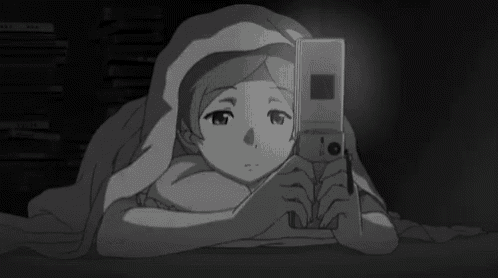 a girl is laying under a blanket and looking at a cell phone