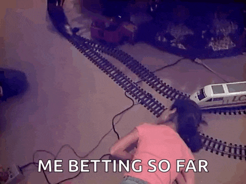 a little girl is laying on the floor playing with a toy train set and says me betting so far