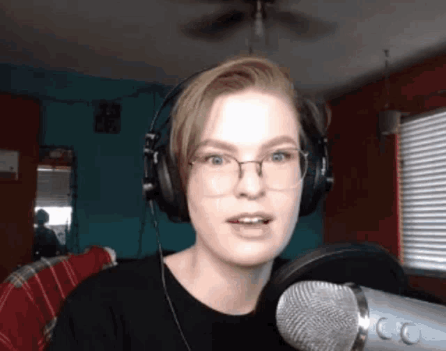 a woman wearing headphones stands in front of a microphone