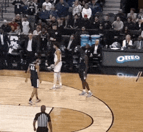 a basketball game is being played on a court with a oreo sign in the stands .