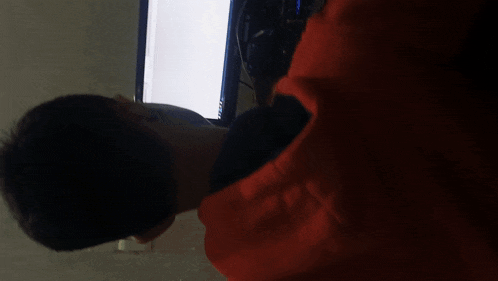 a man in a red sweatshirt is using a tablet and a computer