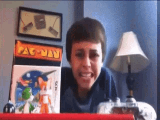 a boy is sitting in front of a pac-man arcade machine