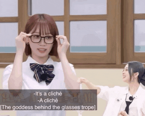 a girl wearing glasses is standing in front of a window .