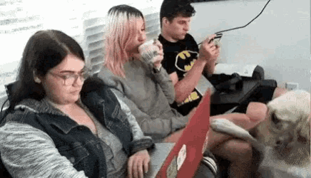 a group of people are sitting on a couch looking at their phones .