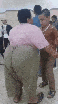 a woman in a pink shirt is dancing with a little boy in a room .