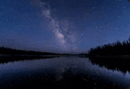 the milky way is reflected in the lake at night .