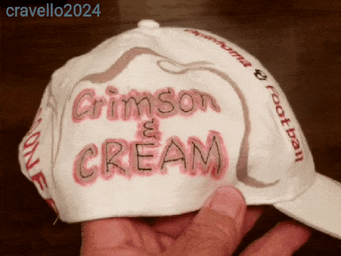 a person is holding a hat that says crimson and cream