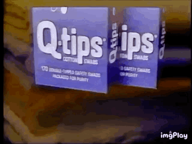 two boxes of q-tips cotton swabs are sitting on a table .