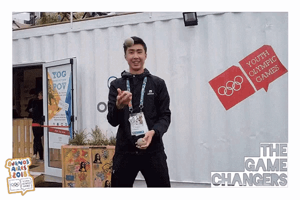 a man is juggling a ball in front of a building that says youth olympic games