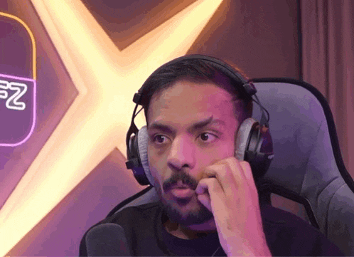 a man wearing headphones is sitting in front of a microphone .