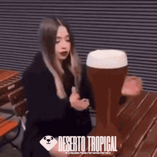 a woman is sitting at a table with a glass of beer in front of her ..