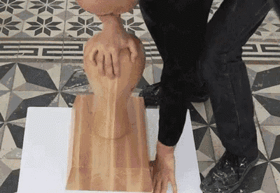 a person is touching a wooden sculpture on a table .