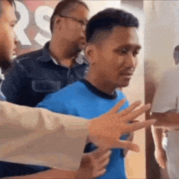 a man in a blue shirt is being escorted by two men .