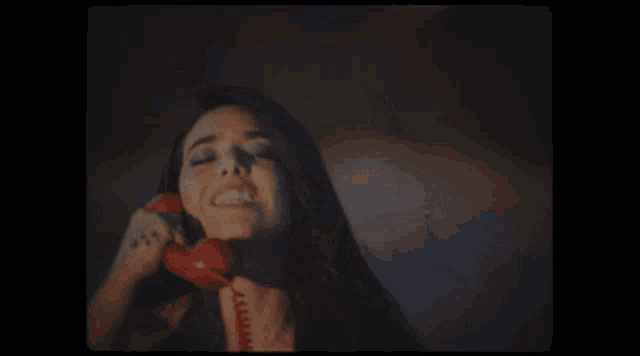 a woman with a tattoo on her arm is talking on a red phone