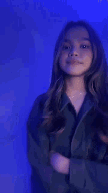 a blurry picture of a woman dancing in a dark room with blue lights .