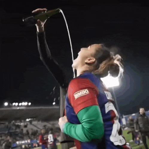 a woman drinking from a bottle with bimbo written on her jersey